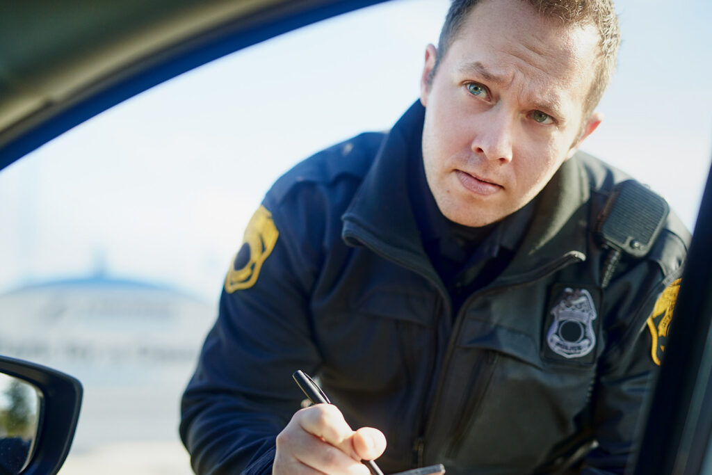 Patrol officer writing a ticket at vehicle window – Traffic Court Buddy defense for overweight truck violations