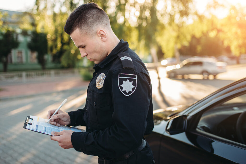 Patrol officer filling out citation paperwork outside vehicle – fight commercial speeding tickets in Michigan